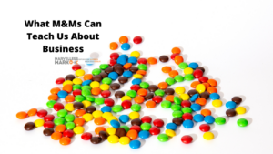 M&Ms poured across a table with the words "what M&Ms can teach us about business" and Marvelless Mark's Keynote Speaker Logo.